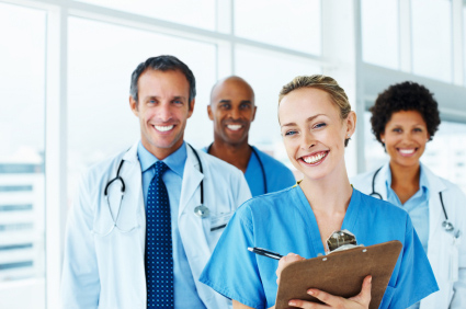 Group of doctors and nurses standing together smiling.