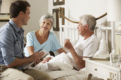 Elderly patient lying in bed and doctor bend over holding the patient’s hands.